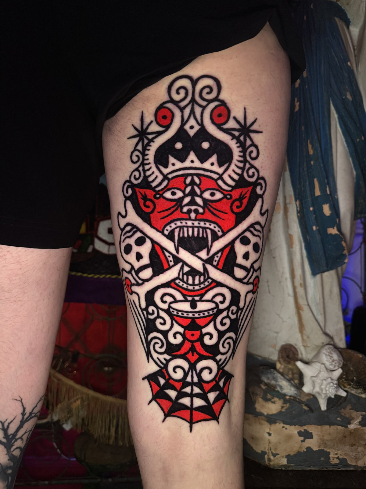 Black and red ornamental mask tattoo on the upper arm