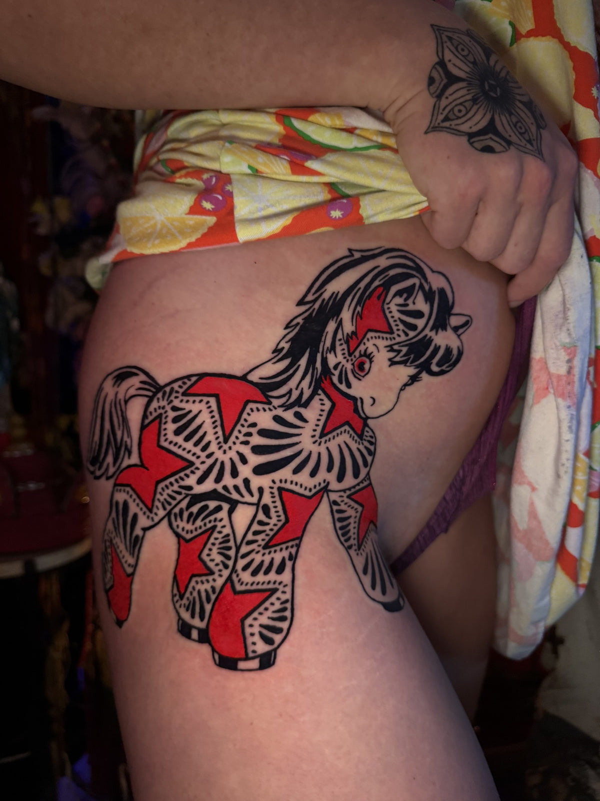 Black and red horse tattoo on the thigh