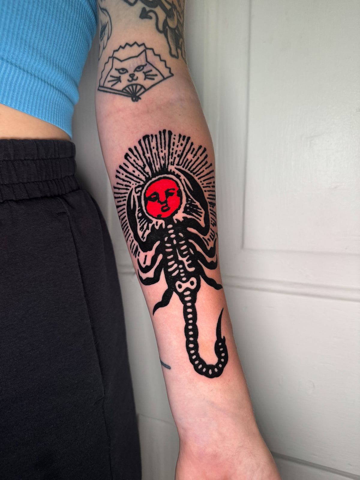 Black and red figure tattoo on the forearm